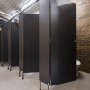 Pedestal-mounted toilet partitions with overhead bracing provide durability in public restrooms.
