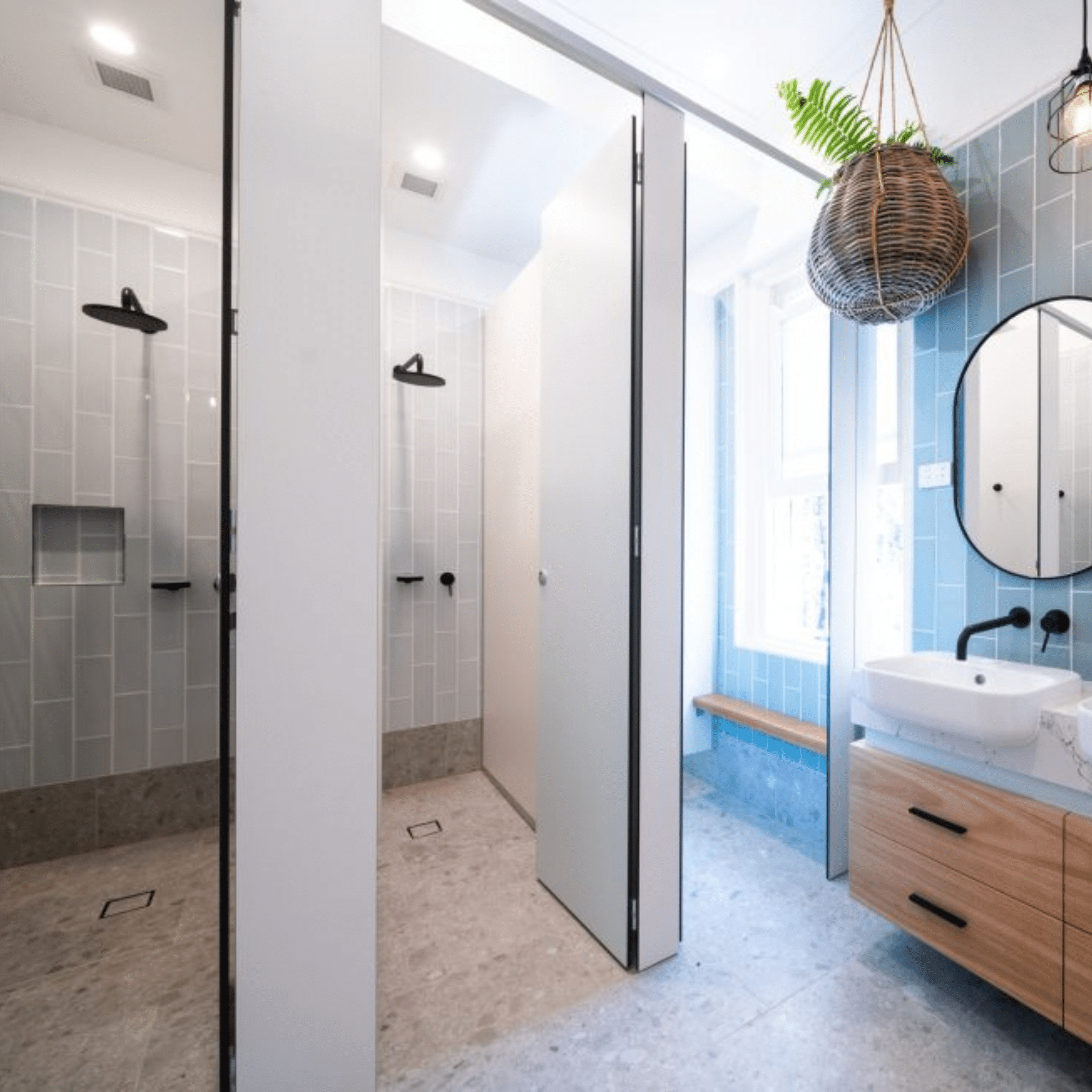 Boarding house bathroom with green tiles, twin round mirrors and a woodgrain compact laminate vanity